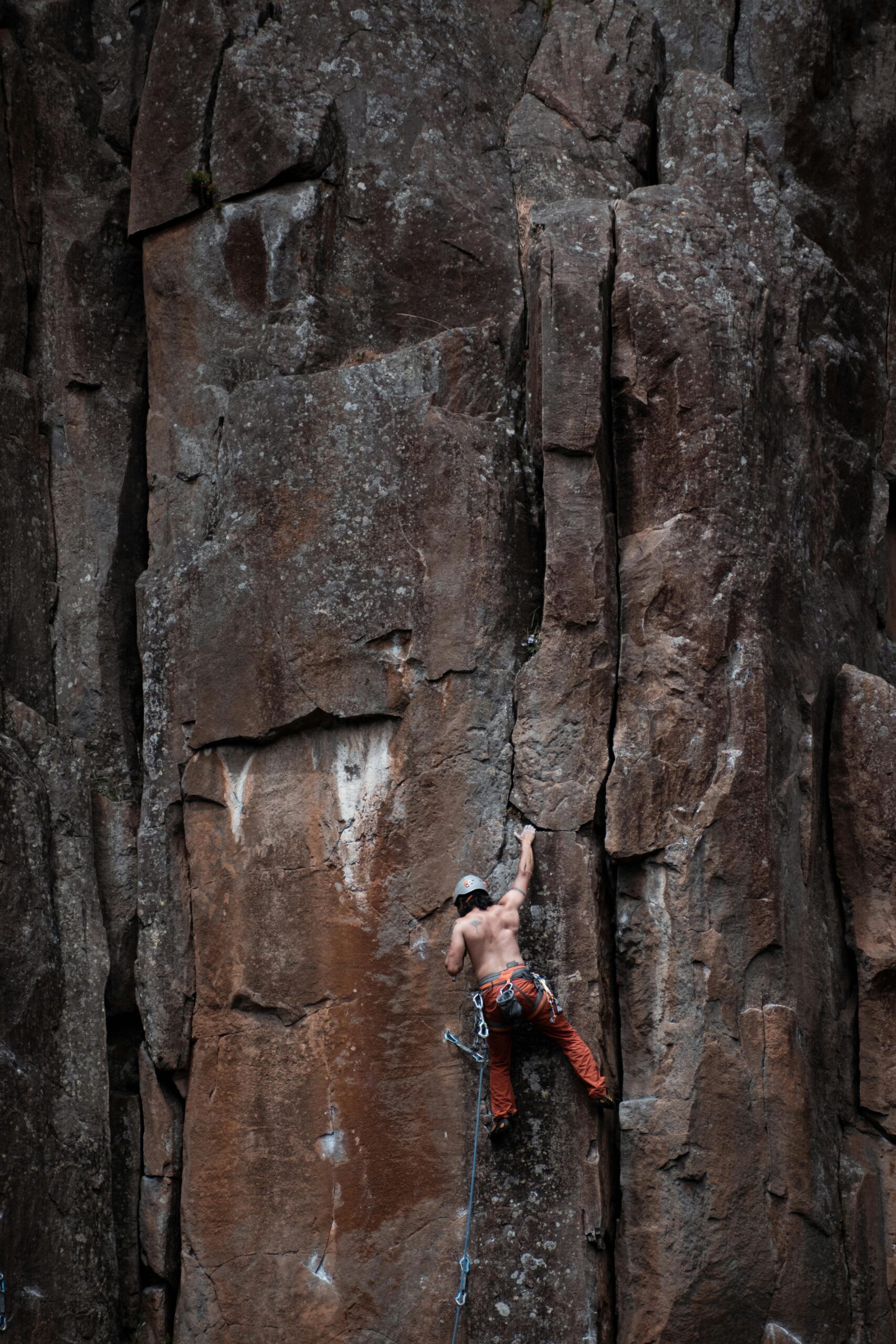 A determined rock climber scales a towering cliff face outdoors in Launceston, Australia.
